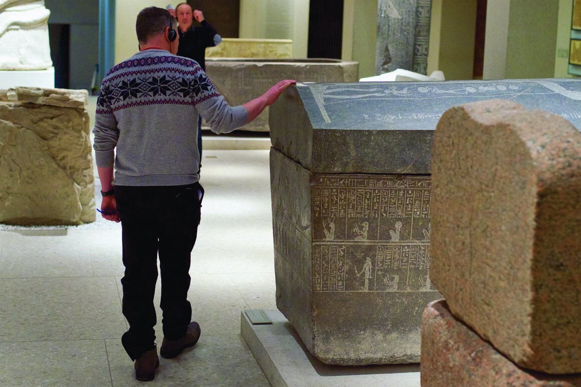 A man runs his hand along a carved sarcophagus at the Neues Museum in Berlin.