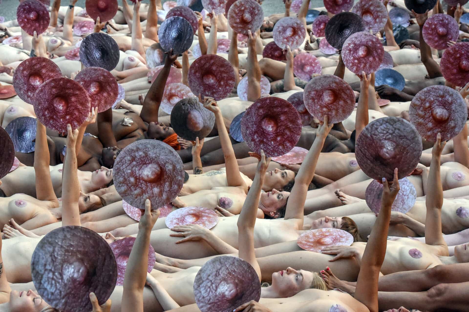 People pose nude holding cut outs of nipples during a photo shoot by artist Spencer Tunick on June 2, 2019 in New York